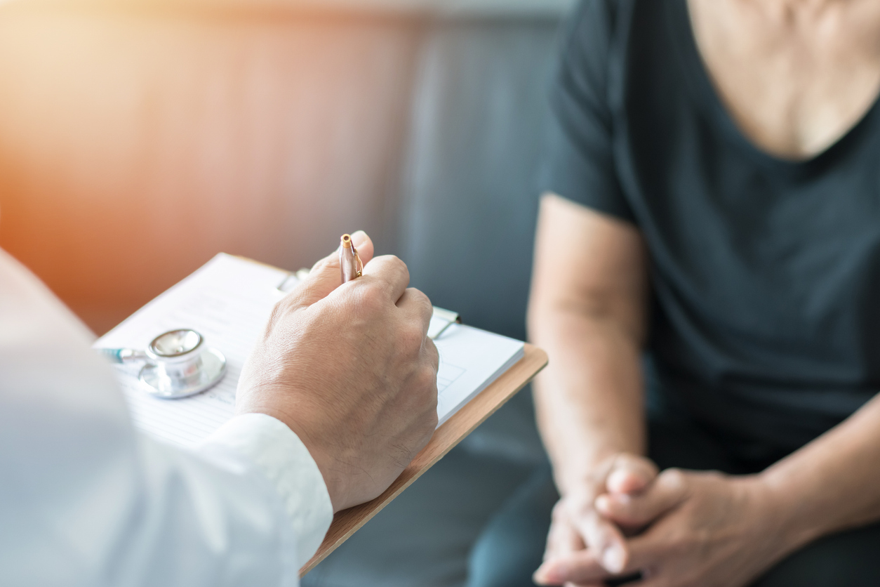 A physician reviewing a clipboard with a client during a private medical consultation