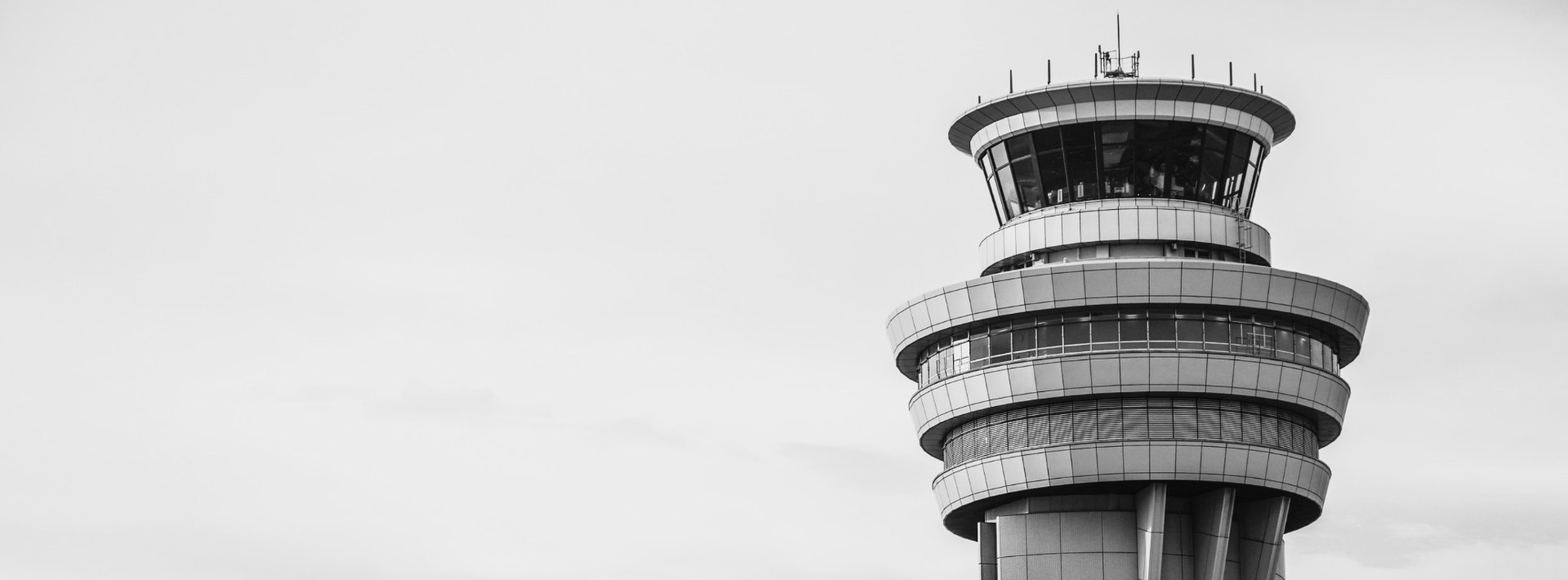 A modern airport control tower against a soft sky
