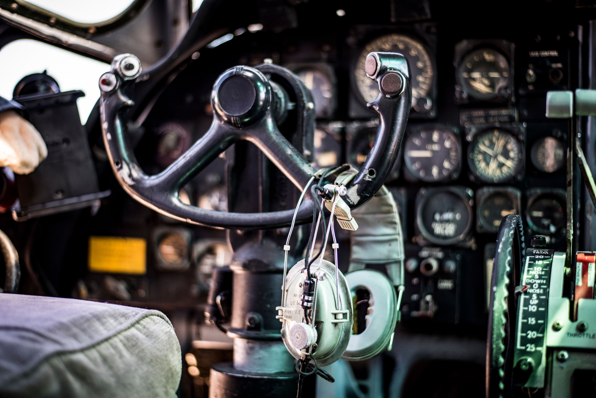 Close-up of a vintage cockpit yoke and headset in front of an instrument panel.