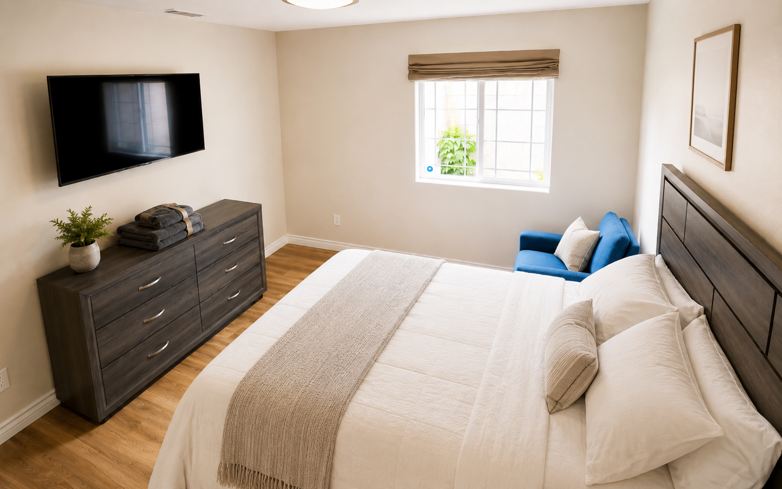 A bright bedroom at Hangar Two with a queen bed and a comfortable blue accent chair