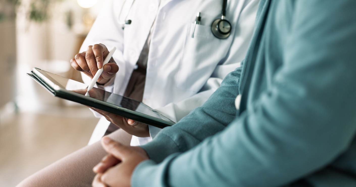 A clinician taking notes on a tablet while sitting beside a client during a private consultation