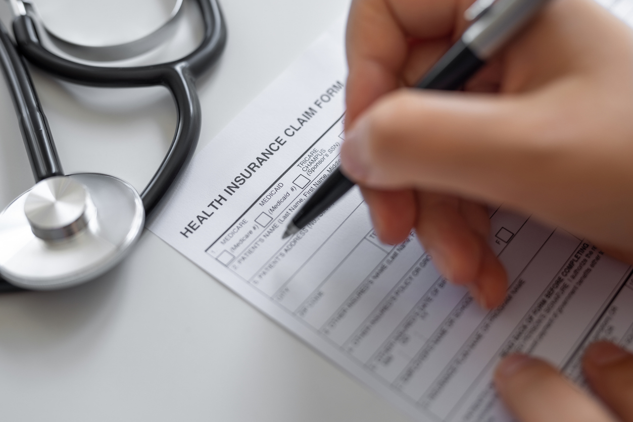 A health insurance claim form being completed beside a stethoscope
